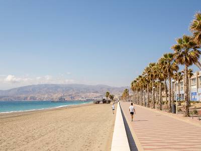 Paseo marítimo y playa urbana en Almería con palmeras y el mar Mediterráneo al fondo